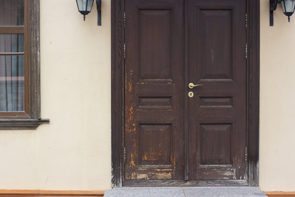 A rustic wooden double door entrance with vintage lanterns, showcasing traditional architectural style.